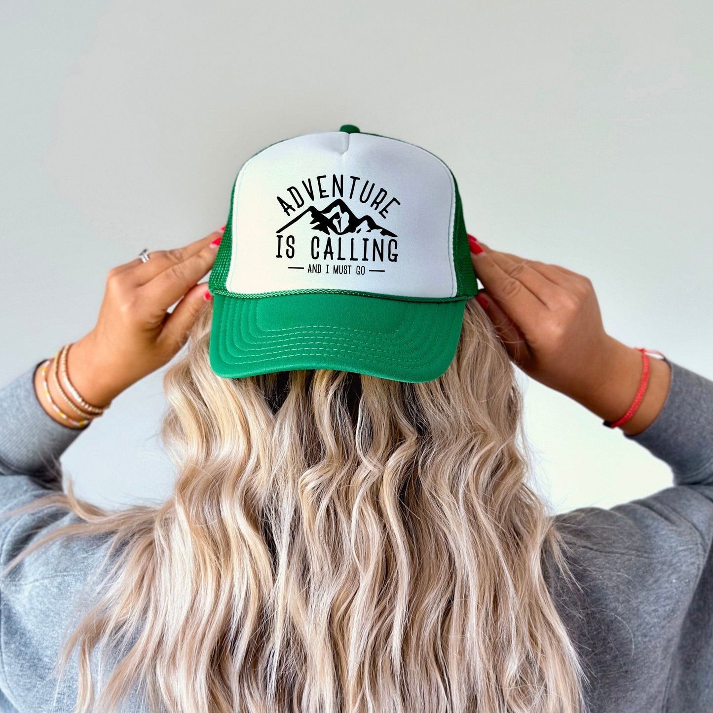 the back of a woman&#39;s head wearing a green and white trucker hat