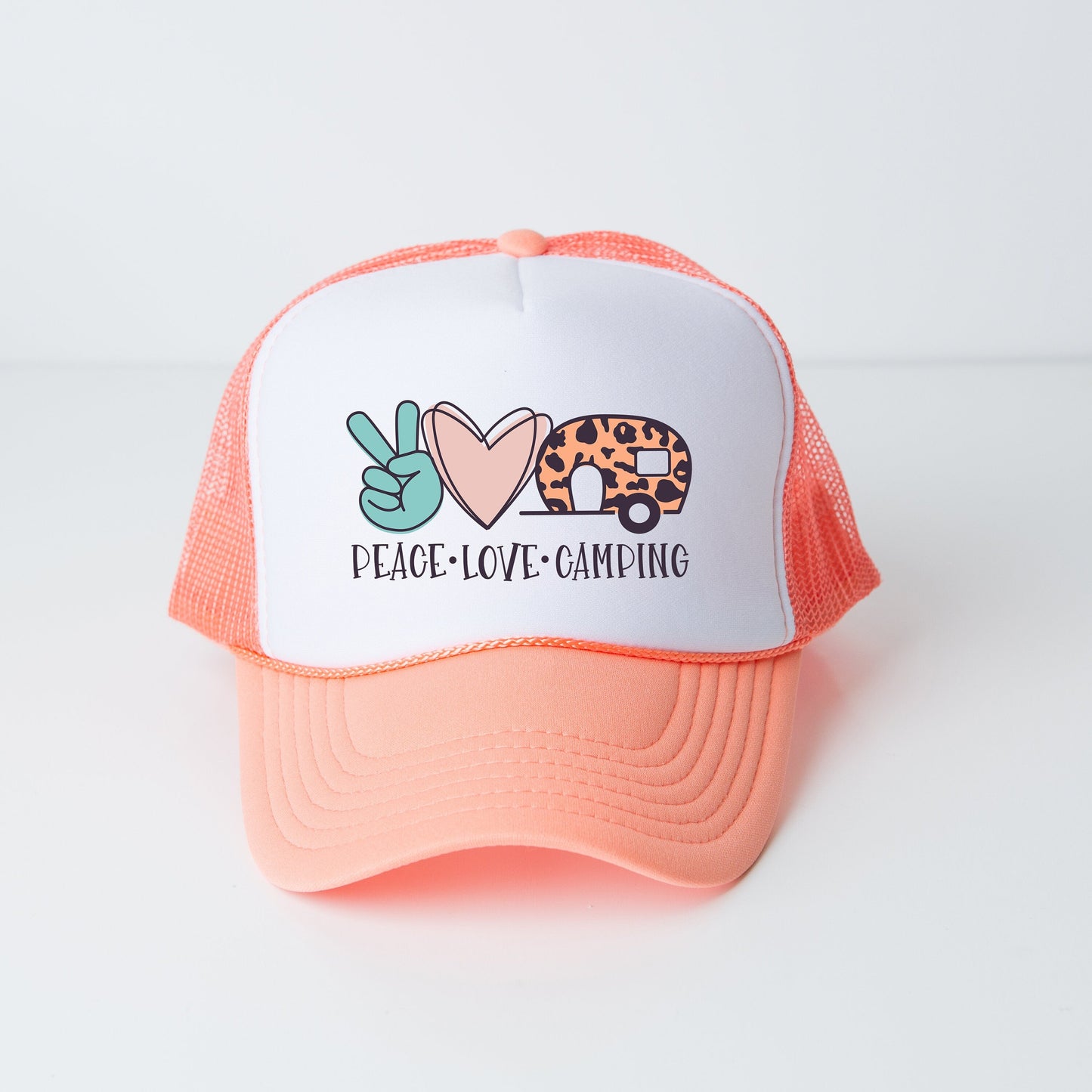 a pink and white trucker hat with a peace love camping design